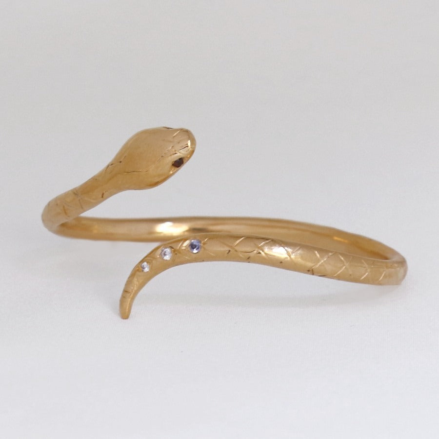 Image is a 24K gold plated snake cuff with garnet eyes, tanzanite and white topaz stones, handmade by Izaskun Zabala.