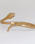 Image is a 24K gold plated snake cuff with garnet eyes, tanzanite and white topaz stones, handmade by Izaskun Zabala.