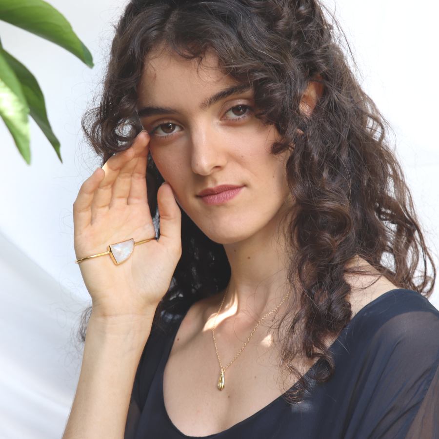 Image is a model wearing a 24K gold plated palm cuff with an asymmetrical moonstone cabochon, handmade by Izaskun  Zabala.