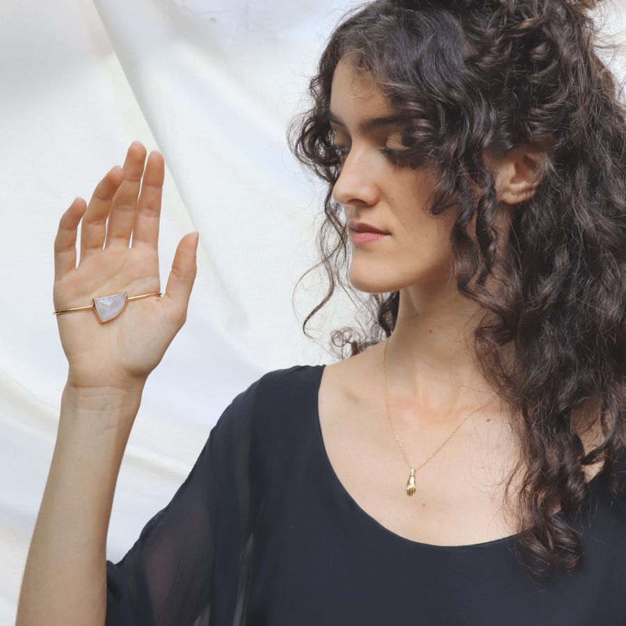 Image is a model wearing a 24K gold plated palm cuff with an asymmetrical moonstone cabochon, handmade by Izaskun  Zabala.