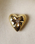 Image is a solid brass heart talisman with a two millimetre centre sapphire and a flower like engraving around the stone.