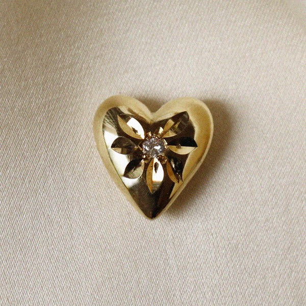 Image is a solid brass heart talisman with a two millimetre centre sapphire and a flower like engraving around the stone.
