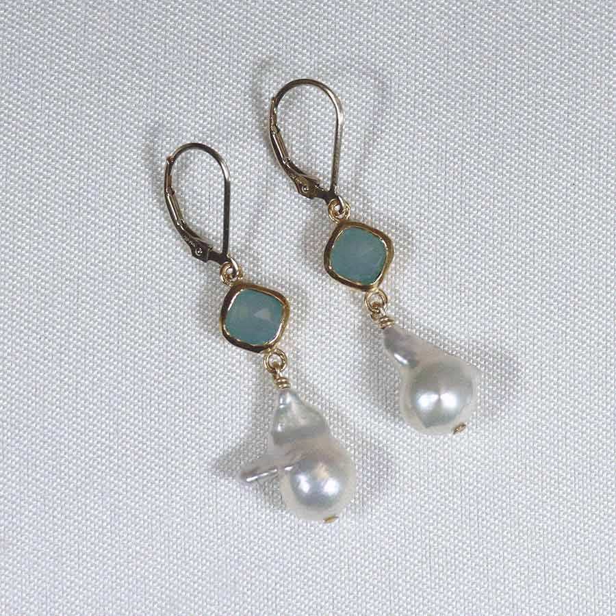 Image is a pair of 24K gold plated earrings with a baroque pearl dangling from a cushion cut stone, handmade by Izaskun Zabala.