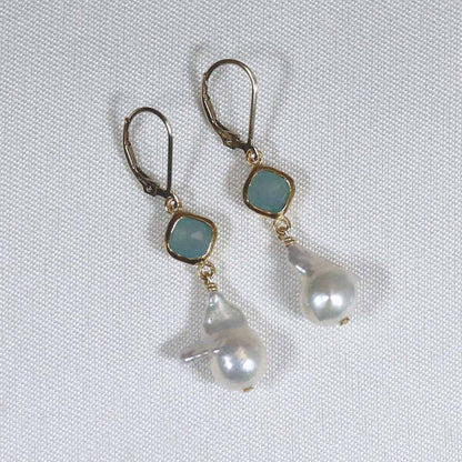 Image is a pair of 24K gold plated earrings with a baroque pearl dangling from a cushion cut stone, handmade by Izaskun Zabala.