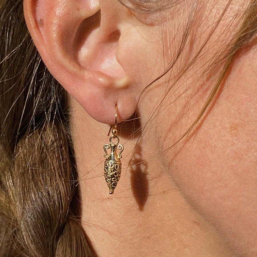 Image is a pair of brass earrings showing a tiny vessel inspired by ancient Greece, with gold filled earwires. Handmade by Izaskun Zabala.