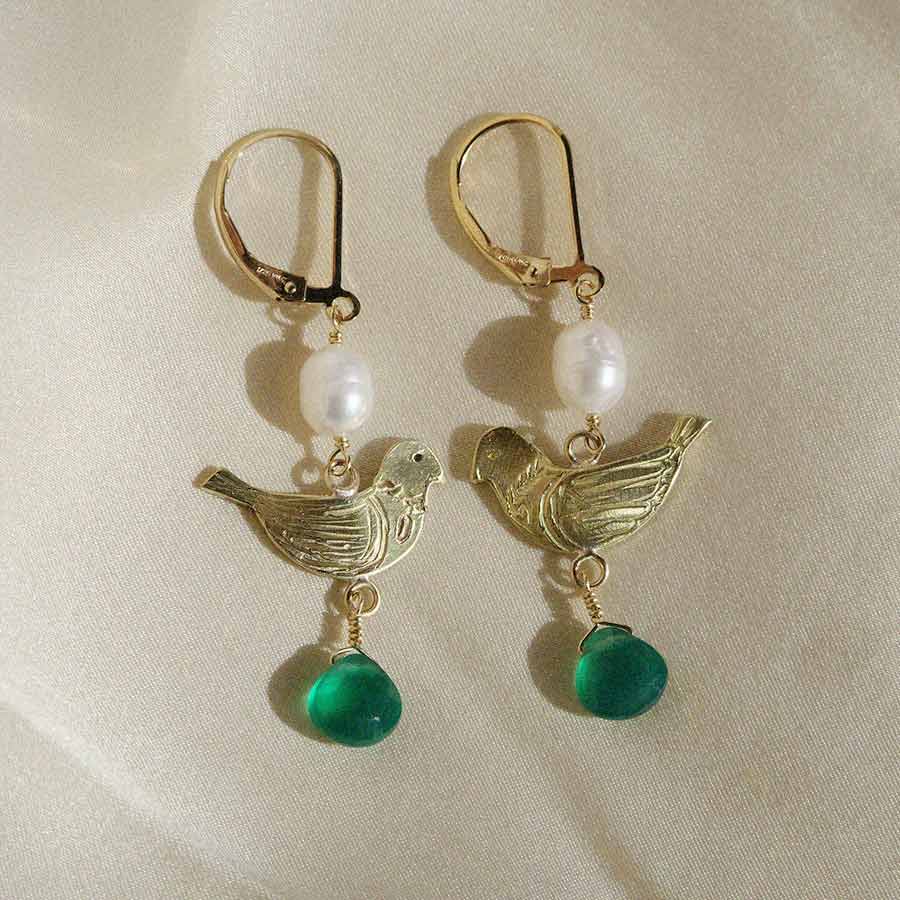 Image is a pair of statement earrings with pearl beads, one-of-kind brass birds and heart shape green onyx, with gold filled earclasp handmade by Izaskun Zabala.