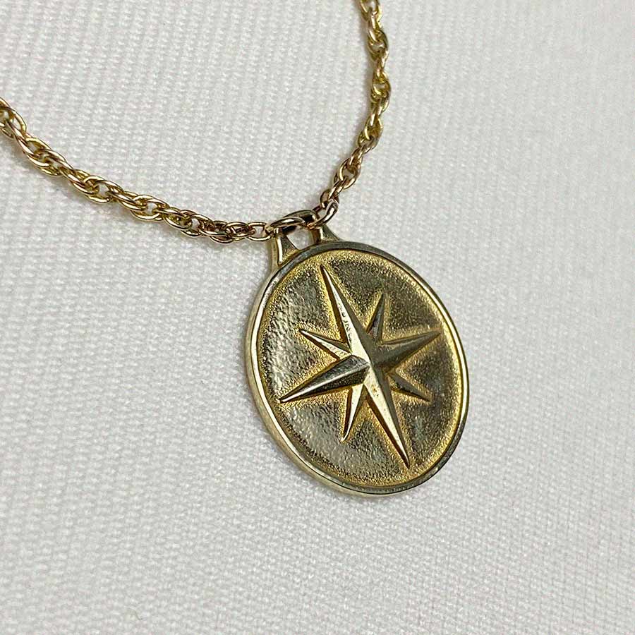 Image is a north star brass medallion with brass chain, handmade by Izaskun Zabala.