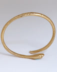 Image is a 24K gold plated snake cuff with turquoise and garnet stones, handmade by Izaskun Zabala.