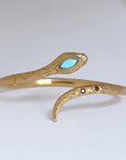 Image is a 24K gold plated snake cuff with turquoise and garnet stones, handmade by Izaskun Zabala.