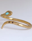 Image is a 24K gold plated snake cuff with turquoise and garnet stones, handmade by Izaskun Zabala.