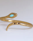 Image is a 24K gold plated snake cuff with turquoise and garnet stones, handmade by Izaskun Zabala.