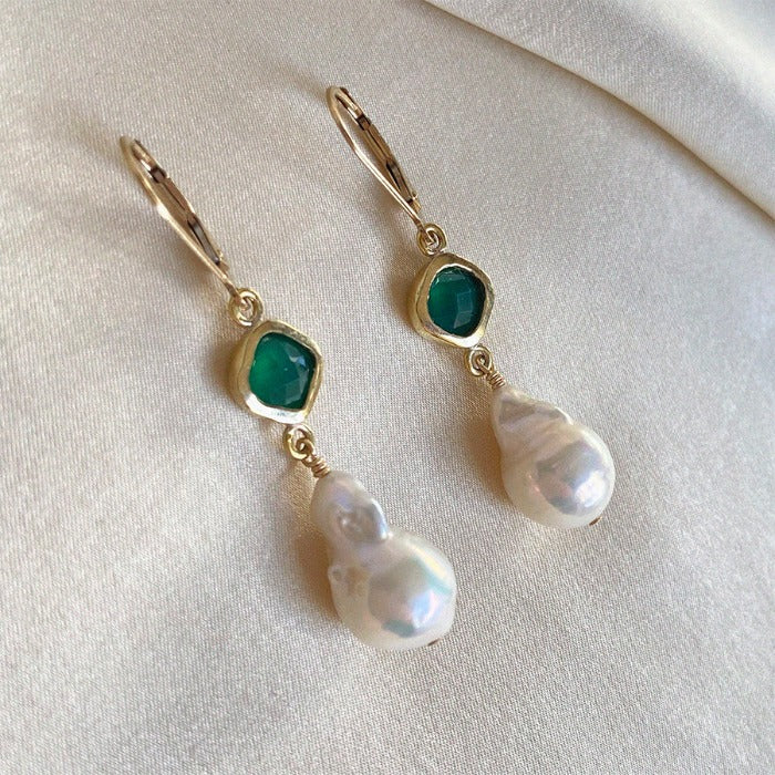 Image is a pair of gold filled earrings with a baroque pearl dangling from a cushion cut green onyx stone, handmade by Izaskun Zabala.