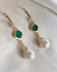 Image is a pair of gold filled earrings with a baroque pearl dangling from a cushion cut green onyx stone, handmade by Izaskun Zabala.