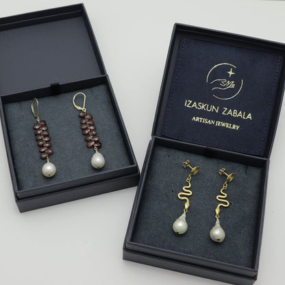 Two pairs of earrings in open jewelry boxes with 'Izaskun Zabala' branding.