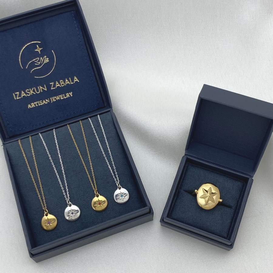 Image is gold-plated and silver birthstone necklaces and a six-pointed star oval golden ring, displayed in the brand&#39;s packaging.
