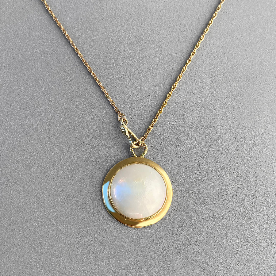Image is a 15mm diameter pearl cabochon pendant with a snake as a front clasp, handmade by Izaskun Zabala.