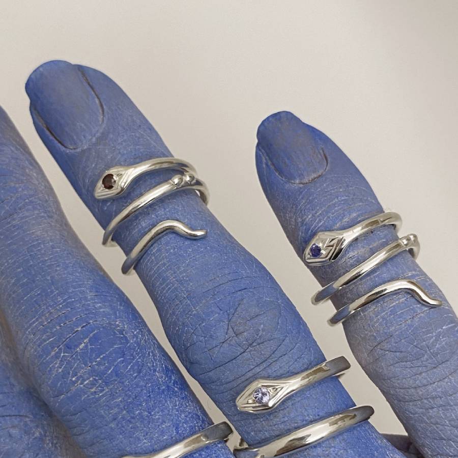 Image is a pair of silver snake pinky rings with gemstone on a hand, handmade by Izaskun Zabala.