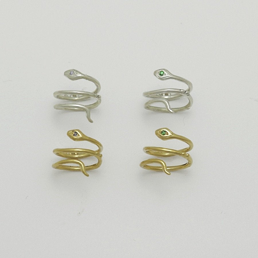 Four snake-shaped knuckle rings in gold plate and silver on a light gray background, handmade by Izaskun Zabala.