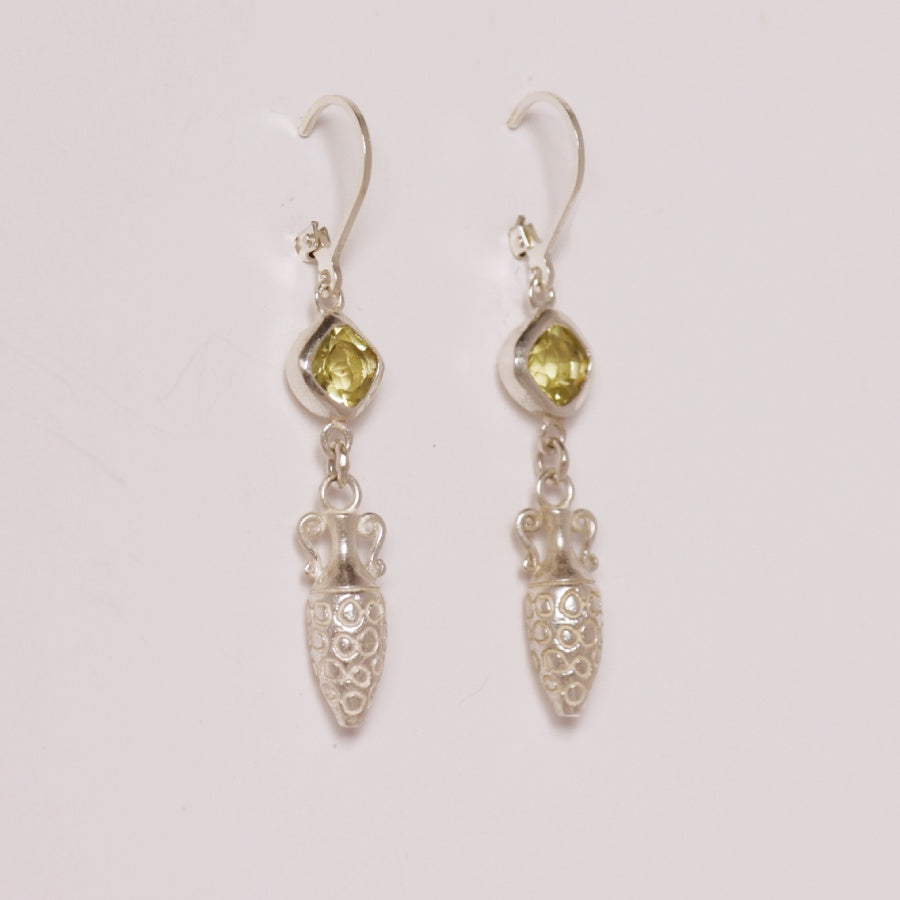 Image is a pair of silver earrings with a carved amphora dangling from a cushion cut citrine stone, handmade by Izaskun Zabala.