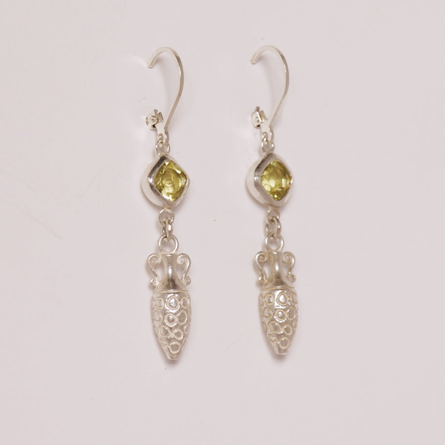 Image is a pair of silver earrings with a carved amphora dangling from a cushion cut lemon quartz stone, handmade by Izaskun Zabala.