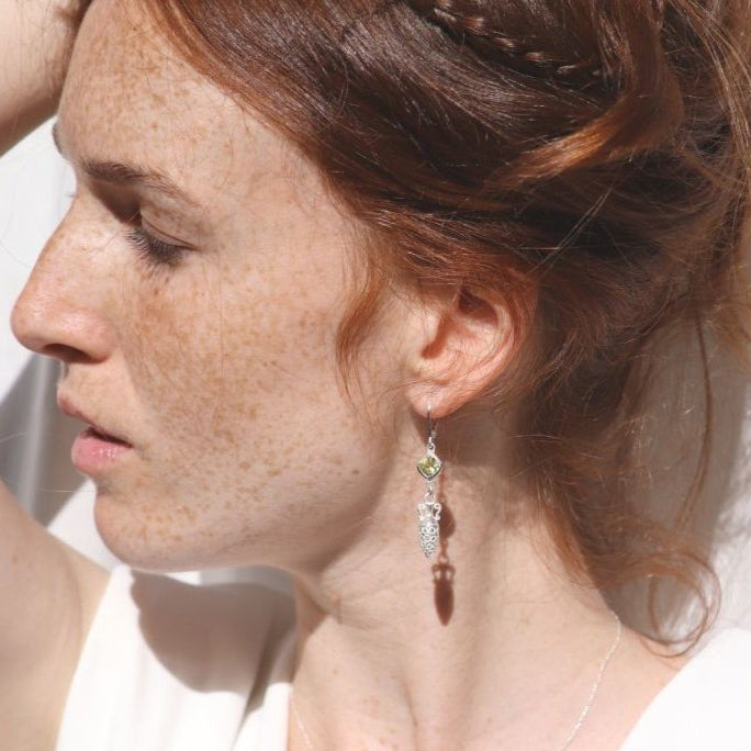 Image is a model wearing silver earrings with a carved amphora dangling from a cushion cut citrine stone, handmade by Izaskun Zabala.