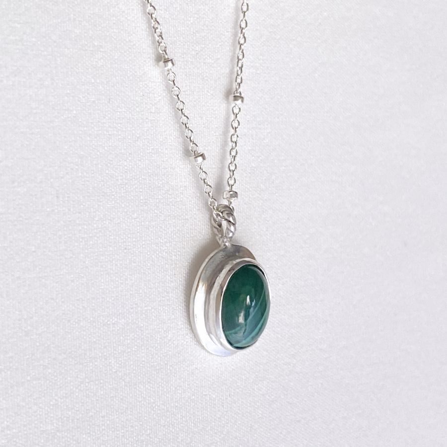 Image is an oval silver pendant with malaquite cabochon and delicate chain, handmade by Izaskun Zabala.