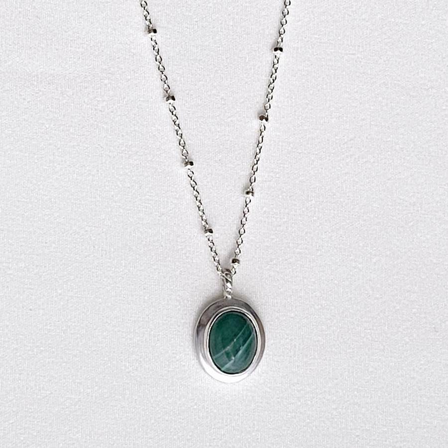 Image is an oval silver pendant with malaquite cabochon and delicate chain, handmade by Izaskun Zabala.