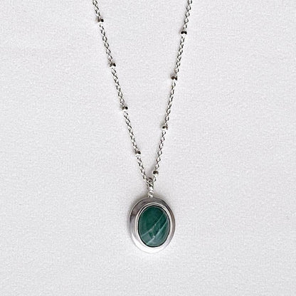 Image is an oval silver pendant with malaquite cabochon and delicate chain, handmade by Izaskun Zabala.