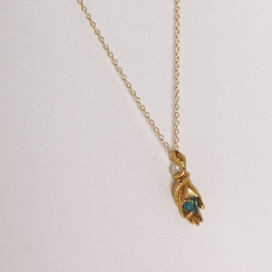 Image is a carved hand and snake pendant with topaz and pearl gold plated necklace, handmade by Izaskun Zabala.