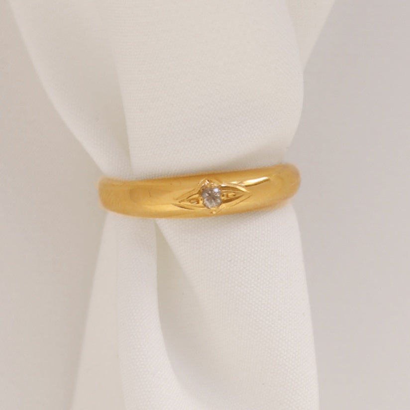 Image is a thin 24K gold plated band ring with an engraved star and white sapphire center stone, handmade by Izaskun Zabala.