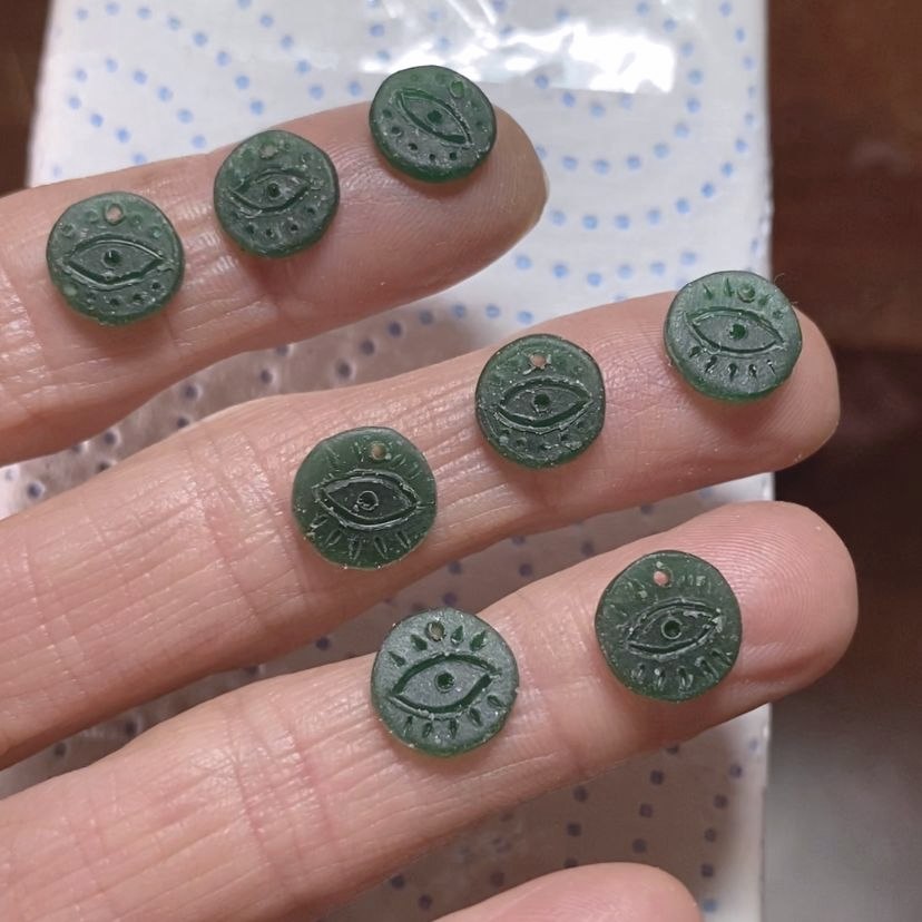 Image is many tiny medallions in wax with an engraved eye, handmade by Izaskun Zabala.