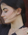Close-up of a woman wearing gold-plated yin yang earrings and ring, artisan made by Izaskun Zabala.