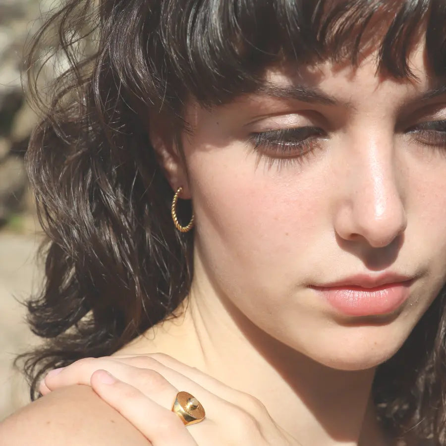 Gold-plated Ariadne Hoops styled on a model with a signet ring