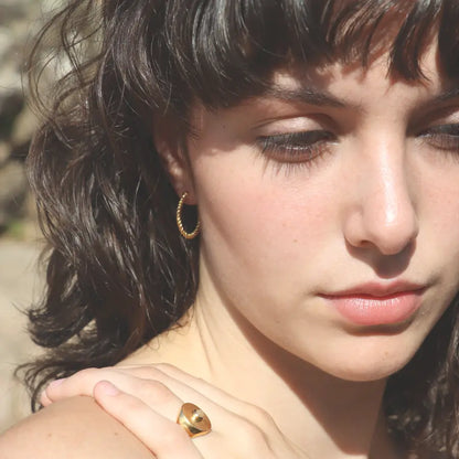 Gold-plated Ariadne Hoops styled on a model with a signet ring