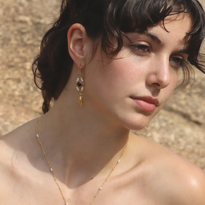 Pair of gold-plated amphora earrings with onyx stones and pearl beads styled on a model