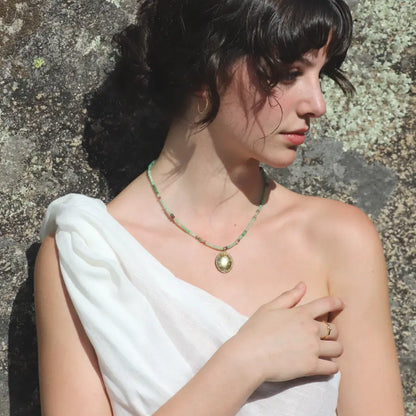 Chrysoprase and tourmaline beaded Gaia Necklace with a gold-plated oval engraved medallion worn on a model