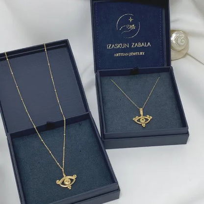 Two handmade eye pendant necklaces on Izaskun Zabala´s branded dark blue packaging boxes.