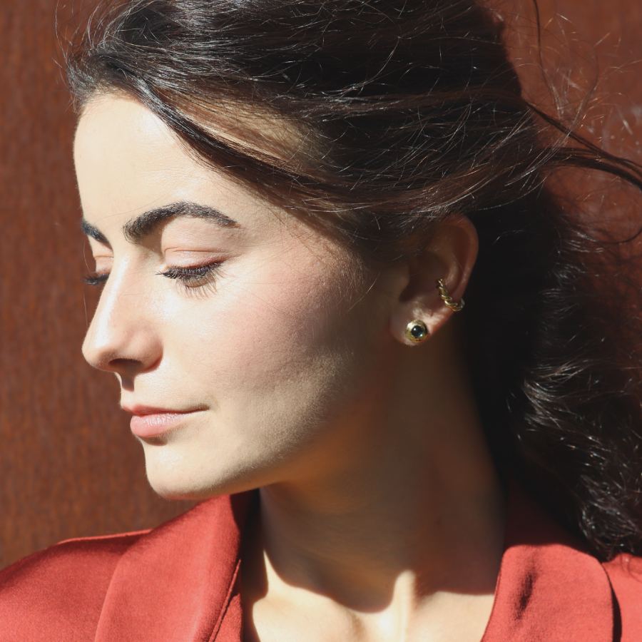 Woman wearing a gold-plated cabochon stud with an ear cuff, handmade by Izaskun Zabala.