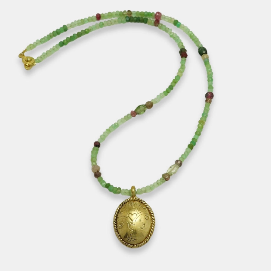 Green and pink gemstone beads necklace with a gold-plated oval engraved medallion, handmade by Izaskun Zabala.