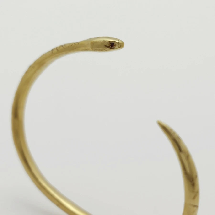 Detail of 24K gold-plated snake-shaped bangle with garnet eyes, handmade by Izaskun Zabala.