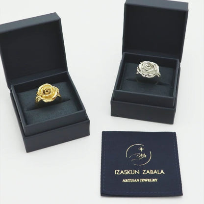 Two handmade rose-shaped rings in dark blue boxes with 'Izaskun Zabala Artisan Jewelry' logo.