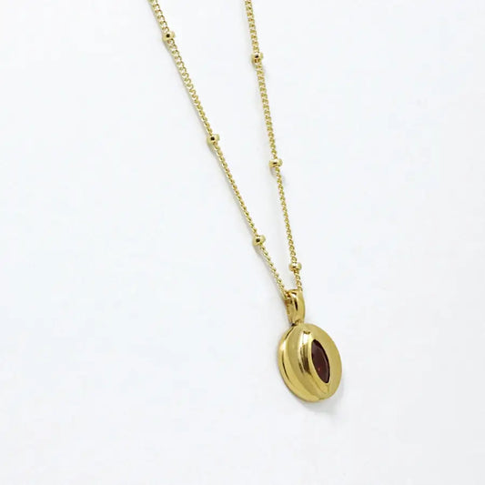 Side view of 24K gold-plated small disk pendant with garnet marquise delicate necklace, handmade by Izaskun Zabala.