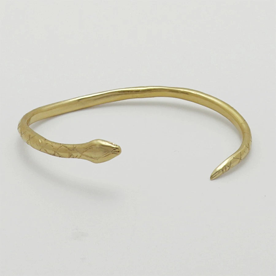 24K gold-plated snake-shaped bangle with garnet eyes, handmade by Izaskun Zabala.