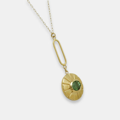 Side view of a gold-plated pendulum necklace with a green turmaline pendant on a white background.