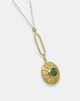 Side view of a gold-plated pendulum necklace with a green turmaline pendant on a white background.