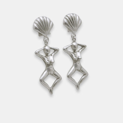 Side view of silver earrings with shell-like tops and female figure dangles, handmade by Izaskun Zabala.