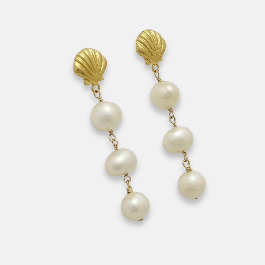 Side view of a pair of gold-plated earrings with shell studs and pearl drops on a white background.
