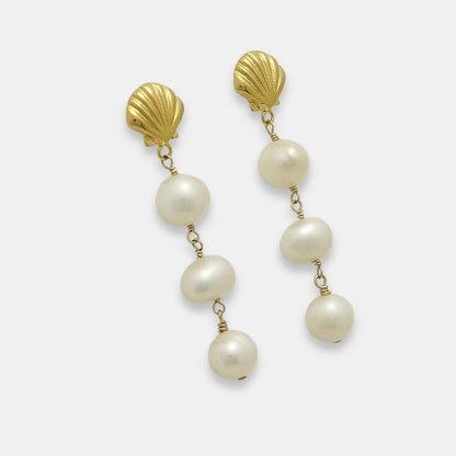 Side view of a pair of gold-plated earrings with shell studs and pearl drops on a white background.