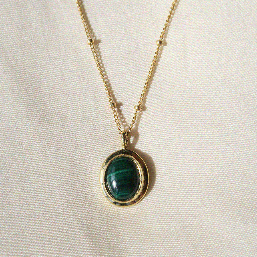 Image is a necklace with an oval malachite cabochon set in a brass pendant with a gold filled chain handmade by Izaskun Zabala.