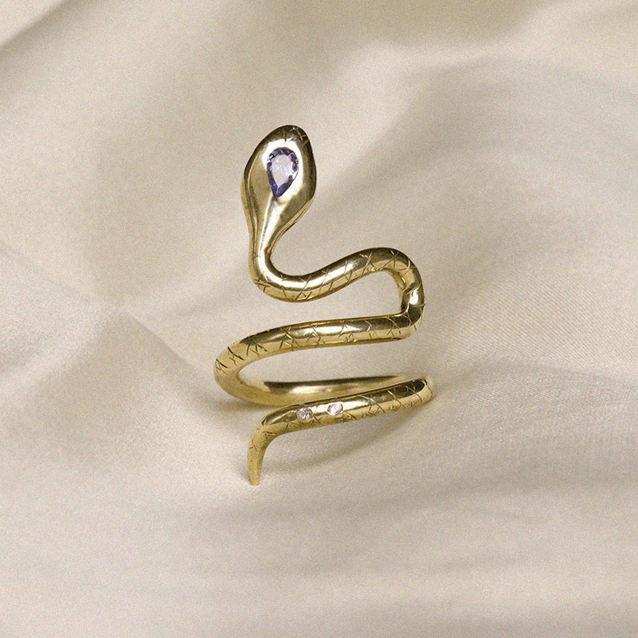 Image is an adjustable brass snake ring with a pear shape tanzanite set in the head and two white sapphires in the tail handmade by Izaskun Zabala.
